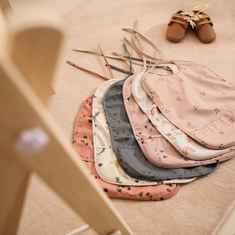 Babador Impermeável Infantil com Bolso Coletor Ajustável Estampas Variadas Unissex